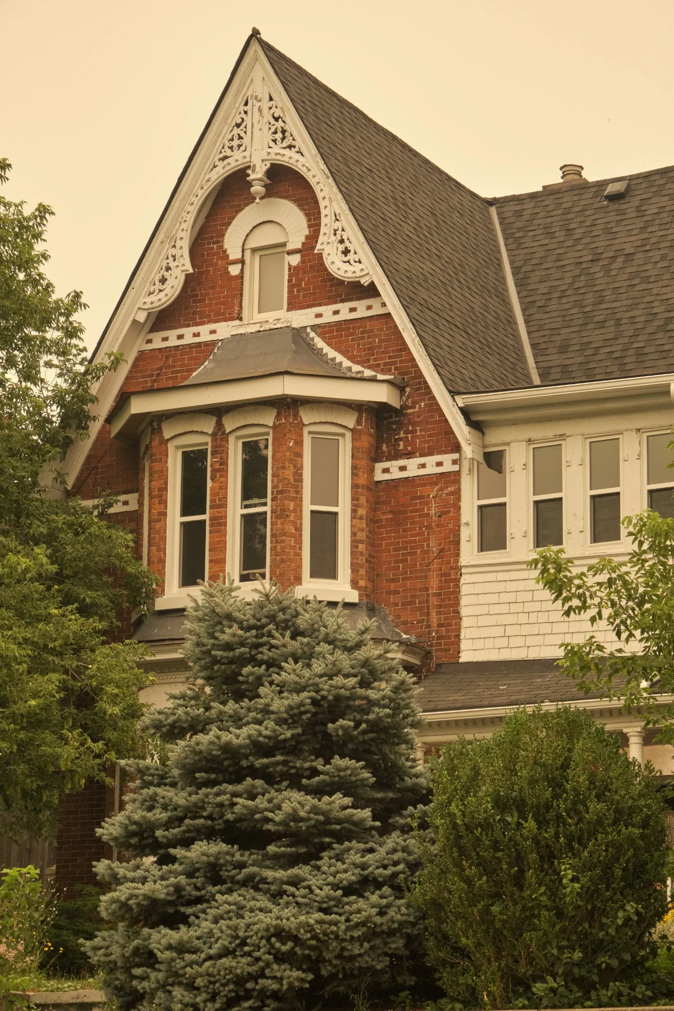 Detailed red brick heritage house with ornate white gable trim